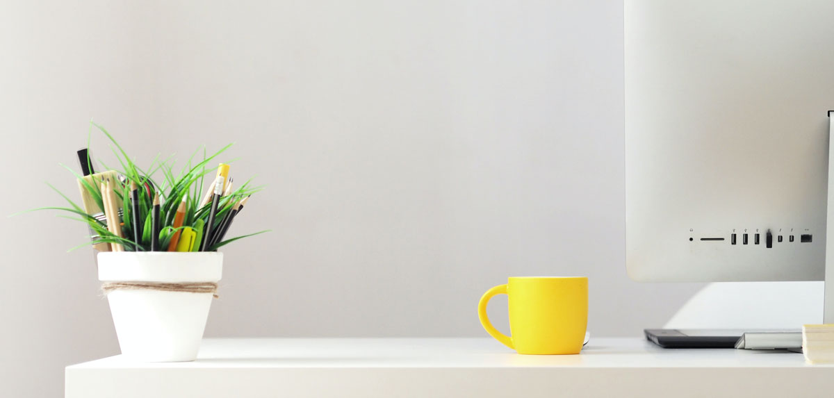 Photographie d'un pot à plante utilisé comme porte crayons, d'une tasse et de l'arrière d'un écran d'ordinateur